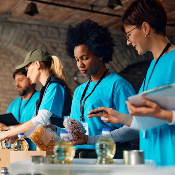 Multiracial group of volunteers packing donated food at humanitarian aid center.